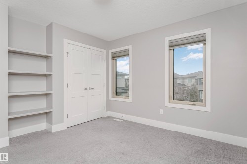 This room features built-in shelving, a pair of white doors, and two windows providing natural light - 3435 Keswick Boulevard, Edmonton, AB 