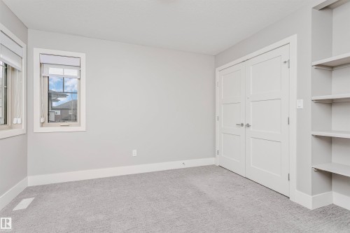 This room features a neutral color palette, grey carpeting, and light-colored walls - 3435 Keswick Boulevard, Edmonton, AB 