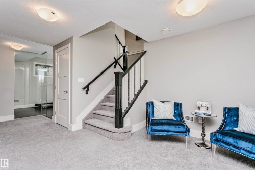 This interior space features light grey walls, light grey carpet, and a staircase with white risers, grey treads, and black handrails - 3435 Keswick Boulevard, Edmonton, AB 
