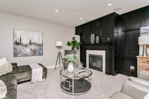 Living area featuring light gray carpeting, recessed lighting, and a fireplace with a light-colored brick surround and a dark wood mantel - 3435 Keswick Boulevard, Edmonton, AB 