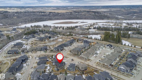 Aerial view of the property and its surrounding neighborhood, showcasing a residential area with a lake and wooded areas in the background - 3435 Keswick Boulevard, Edmonton, AB 