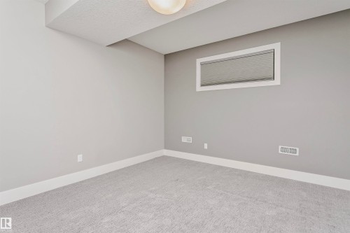 This room features light grey carpeting, light grey walls, and a window with blinds - 3435 Keswick Boulevard, Edmonton, AB 
