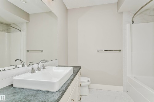 This bathroom features a contemporary vessel sink, chrome fixtures, a spacious vanity with cabinet storage, and a shower-tub combination - 3435 Keswick Boulevard, Edmonton, AB 