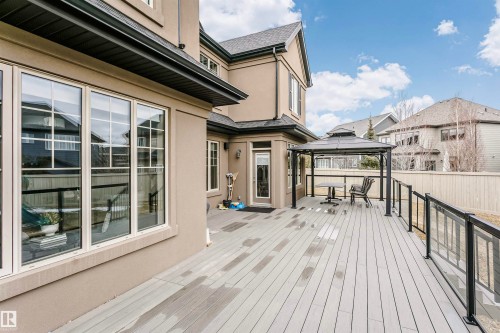 The property features a spacious rear deck with composite decking, glass panel railings, and a sheltered seating area - 3435 Keswick Boulevard, Edmonton, AB 
