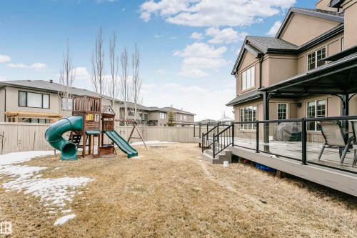 The property features an expansive backyard with a wooden deck, glass railings, and a covered patio area - 3435 Keswick Boulevard, Edmonton, AB 