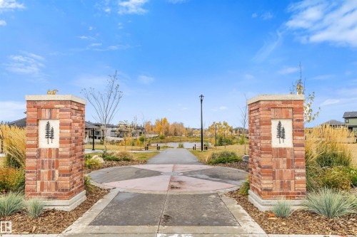 Enjoy community amenities including a path leading to a water feature, framed by brick pillars and landscaping - 3435 Keswick Boulevard, Edmonton, AB 