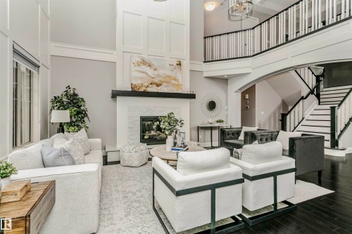 Living room featuring a high ceiling with white paneling, dark wood floors, and a white brick fireplace - 3435 Keswick Boulevard, Edmonton, AB 
