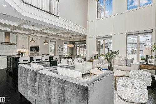 This open-concept living area features high ceilings, dark hardwood floors, and large windows that provide abundant natural light - 3435 Keswick Boulevard, Edmonton, AB 