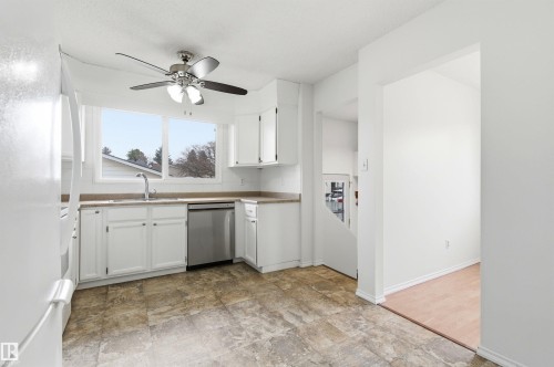The kitchen features white cabinetry, a stainless steel dishwasher, and a ceiling fan - 1707 65 Street, Edmonton, AB - Indoor Photo Showing Kitchen