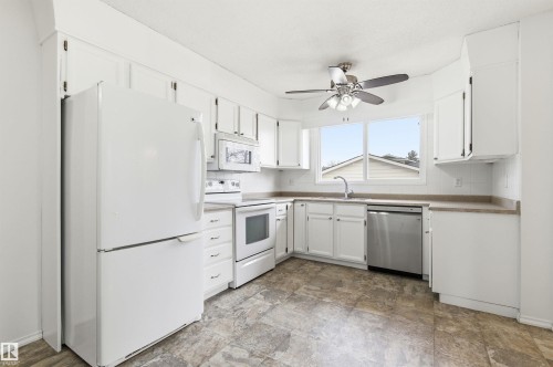 The kitchen features white cabinetry, a refrigerator, an oven, and a microwave - 1707 65 Street, Edmonton, AB - Indoor Photo Showing Kitchen