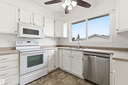 The kitchen features white cabinetry, a large window above the sink, and a stainless steel dishwasher - 1707 65 Street, Edmonton, AB - Indoor Photo Showing Kitchen With Double Sink