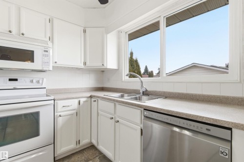 The kitchen features white cabinetry, a double basin sink, and a window providing natural light - 1707 65 Street, Edmonton, AB - Indoor Photo Showing Kitchen With Double Sink