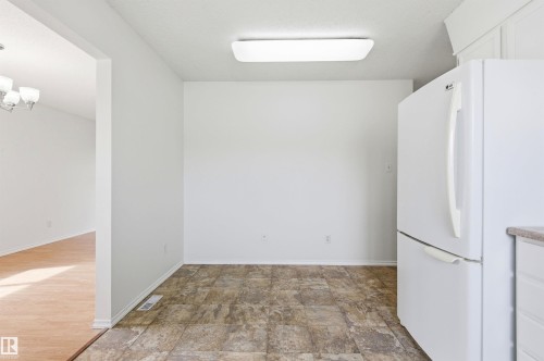 This bright space features a white refrigerator, ceiling-mounted light fixture, and durable flooring - 1707 65 Street, Edmonton, AB - Indoor Photo Showing Other Room