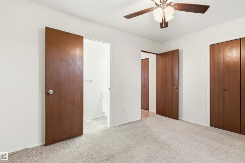 This room features light-colored carpeting, a ceiling fan with integrated lighting, and multiple wooden doors - 1707 65 Street, Edmonton, AB - Indoor