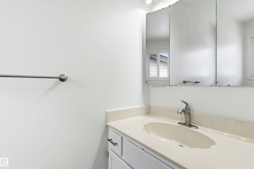 Bathroom vanity featuring a light-colored countertop, an undermount sink, and a brushed nickel faucet - 1707 65 Street, Edmonton, AB - Indoor Photo Showing Bathroom