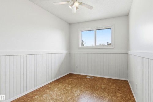This room features light-colored walls with wainscoting, a window providing natural light, and a ceiling fan - 1707 65 Street, Edmonton, AB - Indoor Photo Showing Other Room