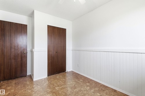 This room features bright white walls with white wainscoting, two wooden doors, and patterned flooring - 1707 65 Street, Edmonton, AB - Indoor Photo Showing Other Room