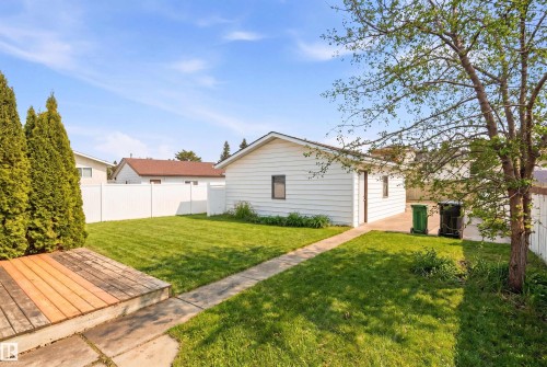 The property features a spacious lawn, a white detached garage, and a wooden deck - 1707 65 Street, Edmonton, AB - Outdoor
