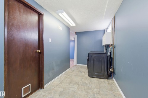 Utility area featuring a dark wood door, light blue walls, and patterned tile flooring - 1707 65 Street, Edmonton, AB - Indoor Photo Showing Other Room