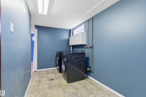 The property features a dedicated laundry area with a washer and dryer, light-colored floor tiling, and a window providing natural light - 1707 65 Street, Edmonton, AB - Indoor Photo Showing Laundry Room