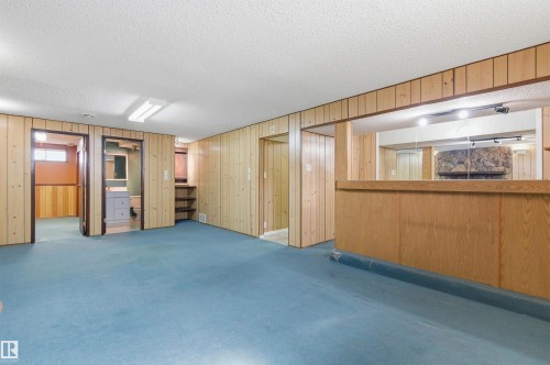 Spacious room featuring wood paneling, a bar area, and blue carpeting - 1707 65 Street, Edmonton, AB - Indoor