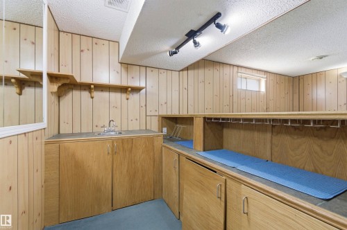 Lower level featuring wood paneled walls, a built-in bar with cabinetry, a sink, and track lighting - 1707 65 Street, Edmonton, AB - Indoor