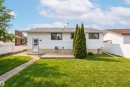 The property features a well-maintained lawn, a white exterior, and a small wooden patio area - 1707 65 Street, Edmonton, AB  - Outdoor 