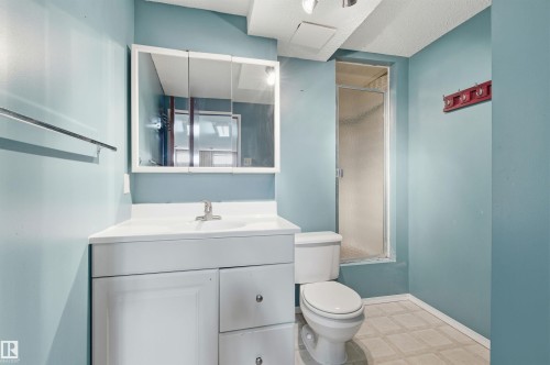 Bathroom featuring a white vanity with a sink, a mirrored medicine cabinet, a toilet, and a shower with a glass door - 1707 65 Street, Edmonton, AB - Indoor Photo Showing Bathroom