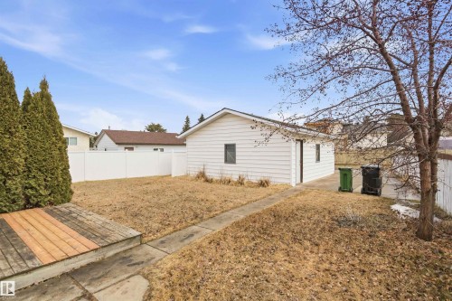 The property features a detached garage with white siding, a white privacy fence, and an outdoor deck with wood planks - 1707 65 Street, Edmonton, AB - Outdoor