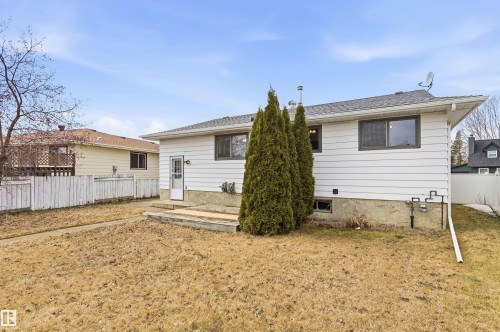 The property features white siding and a light grey shingled roof, with an exterior door leading to a small wooden deck - 1707 65 Street, Edmonton, AB - Outdoor With Exterior