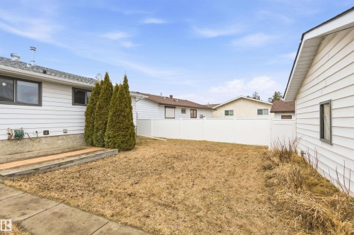 The property features a white exterior with dark-trimmed windows and a white privacy fence - 1707 65 Street, Edmonton, AB - Outdoor With Exterior