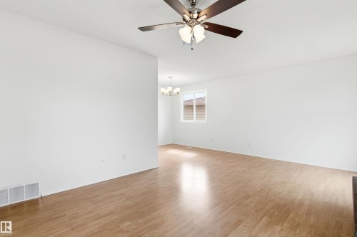 This expansive room features light wood flooring, a ceiling fan with integrated lighting, and white walls - 1707 65 Street, Edmonton, AB - Indoor Photo Showing Other Room
