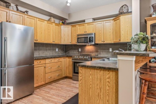 The kitchen features abundant oak cabinetry, a stainless steel refrigerator, and a stainless steel oven with a microwave - 332 612 111 Street, Edmonton, AB - Indoor Photo Showing Kitchen