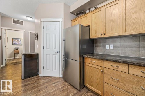 The kitchen features wood cabinetry, a stainless steel refrigerator, and dark countertops - 332 612 111 Street, Edmonton, AB - Indoor Photo Showing Kitchen