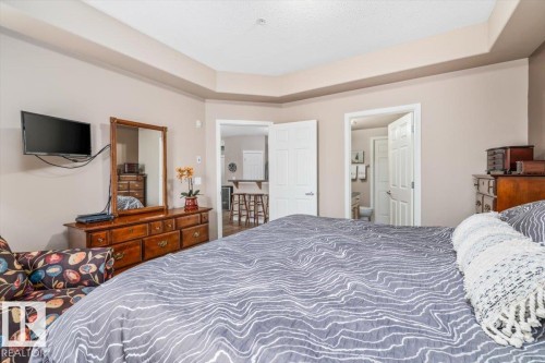 The bedroom features a tray ceiling, light neutral-toned walls, and white paneled doors - 332 612 111 Street, Edmonton, AB - Indoor Photo Showing Bedroom