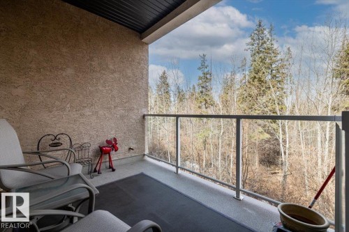 The property features a balcony with a glass railing, providing views of surrounding trees and a bright sky - 332 612 111 Street, Edmonton, AB - Outdoor