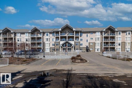 The property features a multi-story exterior with a combination of light-colored siding and stone accents, complemented by balconies with glass railings - 332 612 111 Street, Edmonton, AB - Outdoor With Facade
