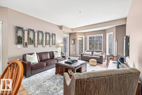 Living area featuring light-colored walls, large windows, and hardwood floors - 332 612 111 Street, Edmonton, AB - Indoor Photo Showing Living Room