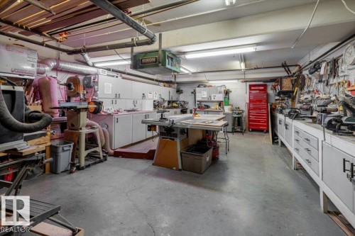The property features a spacious workshop area with concrete flooring, extensive built-in cabinetry, and overhead fluorescent lighting - 332 612 111 Street, Edmonton, AB - Indoor Photo Showing Garage
