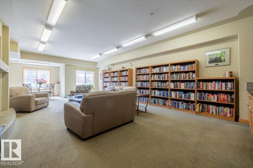 Spacious common room featuring extensive built-in bookshelves, large windows, and neutral carpeting - 332 612 111 Street, Edmonton, AB - Indoor