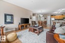 The open concept living area features hardwood floors, a light-colored area rug, and a kitchen with wooden cabinetry - 332 612 111 Street, Edmonton, AB  - Indoor Photo Showing Living Room 