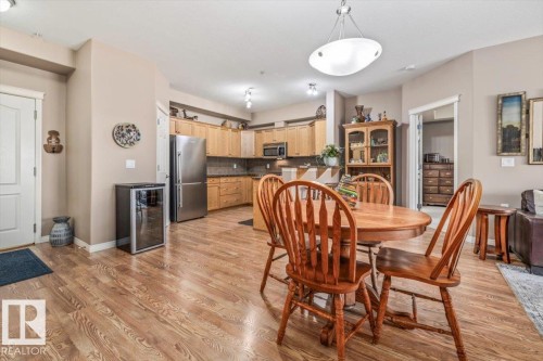 Open concept living area featuring hardwood flooring, recessed lighting, and a kitchen with stainless steel appliances and wood cabinetry - 332 612 111 Street, Edmonton, AB - Indoor Photo Showing Dining Room