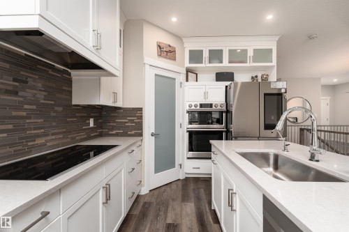 Modern kitchen featuring white cabinetry, a stainless steel sink with a high arc faucet, stainless steel appliances, and a tiled backsplash - 6193 Carr Road, Edmonton, AB - Indoor Photo Showing Kitchen With Upgraded Kitchen