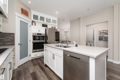 The kitchen features an island with a stainless steel sink and dishwasher, white cabinetry, and light-colored countertops - 6193 Carr Road, Edmonton, AB - Indoor Photo Showing Kitchen With Upgraded Kitchen