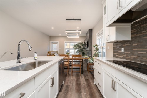 The kitchen features white cabinetry, stainless steel appliances, and a tiled backsplash - 6193 Carr Road, Edmonton, AB - Indoor Photo Showing Kitchen