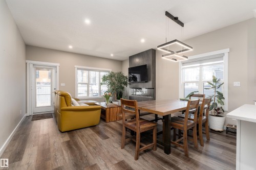 The living area features wood-look flooring, recessed lighting, and a modern fireplace with a wall-mounted television above - 6193 Carr Road, Edmonton, AB - Indoor