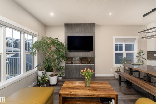 Living area featuring wide plank flooring, large windows with white trim, and a contemporary fireplace - 6193 Carr Road, Edmonton, AB - Indoor Photo Showing Living Room