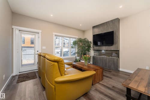 The living area features wood-style flooring, recessed lighting, and a contemporary fireplace with a mounted television above - 6193 Carr Road, Edmonton, AB - Indoor Photo Showing Living Room