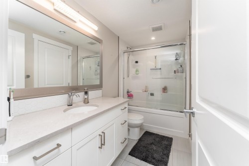 Full Bathroom .The bathroom features a vanity with a white countertop and white cabinetry, a large mirror, and a bathtub with a clear glass enclosure - 6193 Carr Road, Edmonton, AB - Indoor Photo Showing Bathroom