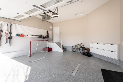 Spacious garage featuring a durable epoxy floor, integrated wall storage, and a staircase - 6193 Carr Road, Edmonton, AB - Indoor Photo Showing Garage